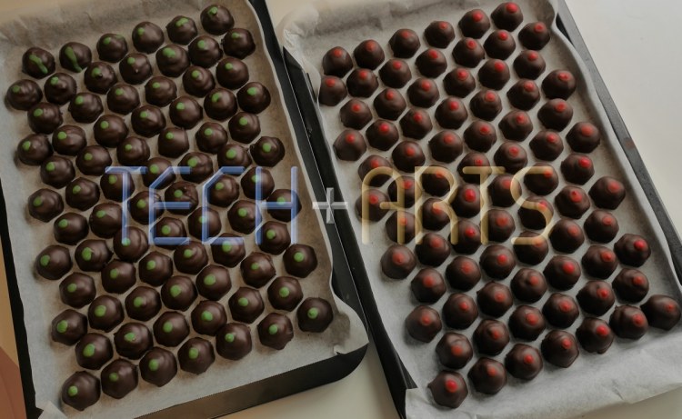 Finished chocolates on trays, with red and green dots to distinguish between flavours